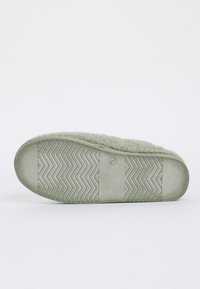 Fuzzy gray slipper showing textured rubber sole with zigzag pattern and grip sections on a plain white background.