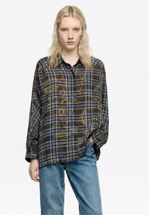 Camisa de manga larga con botones en marrón oscuro, con un diseño de cuadros azules y patrones abstractos en dorado. Corte holgado, fabricada en un tejido ligero y semi-translúcido.