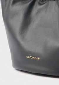 Borsa in pelle nera con finitura testurizzata, caratterizzata da dettagli con logo dorato. Il design presenta una chiusura superiore arricciata e una forma morbida e arrotondata.