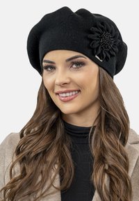 Berretto lavorato a maglia nero con design texturizzato e una grande accentuazione floreale in tessuto con dettagli di perline su un lato.