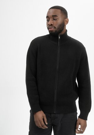 Zwarte zip-up trui met een gestructureerd rib dessin, hoge kraag en nauwsluitende manchetten, gemaakt van zacht breimateriaal.