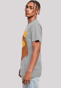 Siva pamučna majica s grafikom šarenog lava i natpisom. Majica ima okrugli izrez i kratke rukave, s opuštenim krojem.