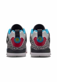 Un paio di sneakers viste da dietro, con colori bianco, rosso, nero e blu, caratterizzate da accenti grigi a motivi e loghi circolari blu.