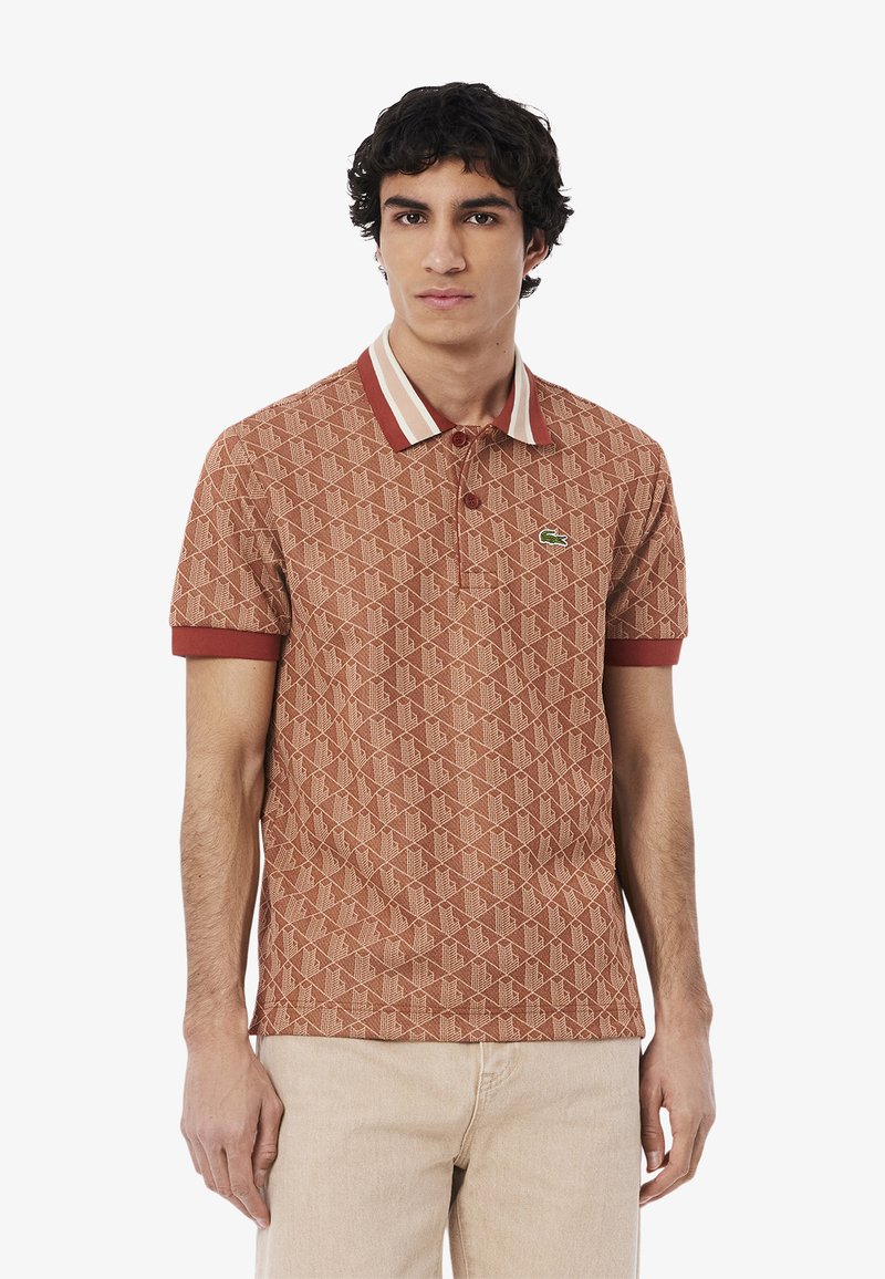 Korte mouwen polo shirt in roestkleur met een geometrisch patroon, contrasterende gestreepte kraag en drieknoopsluiting. Heeft een klein logo.