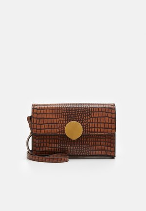 Borsa in pelle marrone con motivo coccodrillo e chiusura circolare dorata, dotata di tracolla removibile e forma rettangolare.