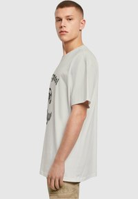 Lichtgrijze T-shirt met korte mouwen, voorzien van zwarte tekst en grafische print aan de voorkant, met een relaxte pasvorm en zachte katoenen stof.