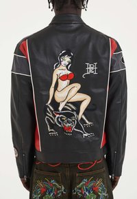 Sorte læderjakke med røde accenter, en broderet pin-up pige og en panter på ryggen, detaljeret syning og en tætsiddende design.