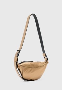Metallic guld crossbody taske med en glat tekstur, sort justerbar rem og lynlåslukning. Bølgeformet med et minimalistisk design.