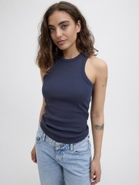 Marineblå ribbestrikket tanktopp med høy hals og ermeless design, kombinert med lyseblå høytlivsjeans.