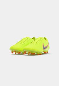 Botas de fútbol amarillas con parte superior texturizada, cinco ojales y un prominente swoosh negro. Presenta acentos naranjas en la suela para mayor tracción.