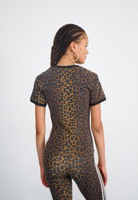 Top de estampado de leopardo con un diseño ajustado, mangas cortas y ribetes negros. Hecho de una tela suave y elástica para mayor comodidad.