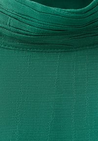 Približek teksture zelene tkanine z gostim, navpičnim in diagonalnim vzorcem šivov ter večplastnimi šivi.