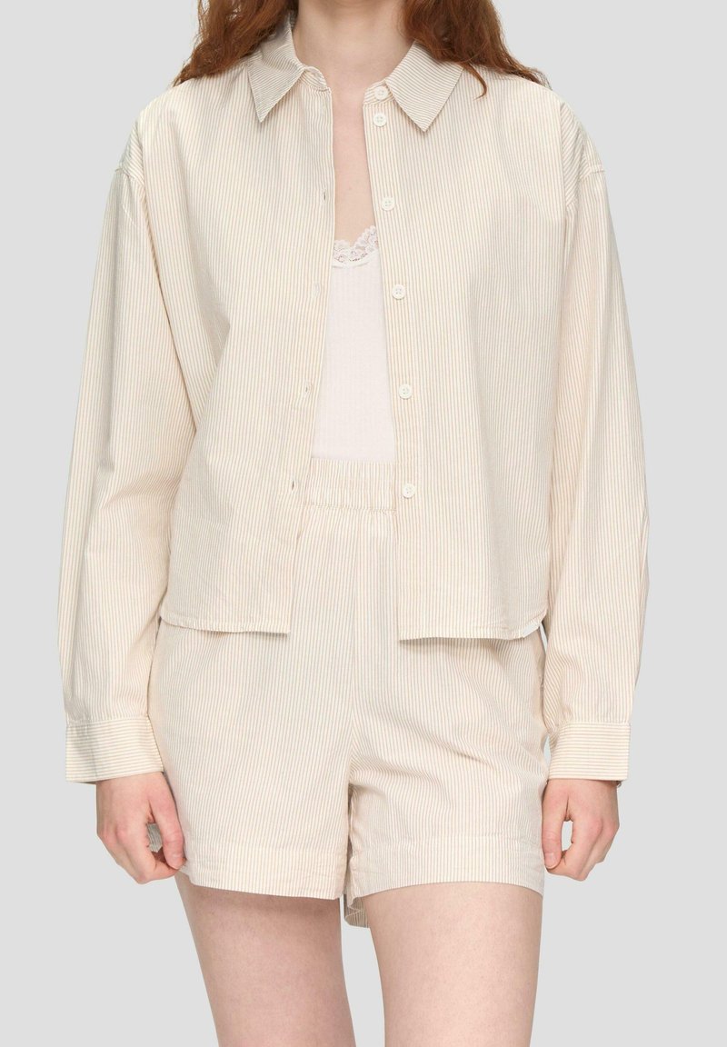 Camisa a rayas de color beige claro con cuello y botones, combinada con pantalones cortos a juego. Tejido suave con un corte relajado y una textura sutil.
