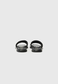 Black thong sandals with braided straps, flat sole, and smooth finish. Minimalist design with a simple and elegant appearance.