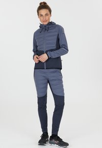 Hættejakke og tætsiddende bukser i to nuancer af blå-grå, med kviltet krop, slank tekstur og kontrasterende paneldesign.