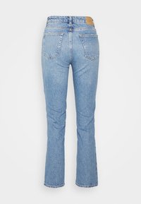 Jeans de denim azul claro com cintura ajustada, pernas retas, design de cinco bolsos e uma pequena etiqueta de tecido na parte de trás.