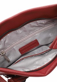 Red leather handbag interior with a zippered pocket, light gray lining featuring subtle patterns, and leather branding label.