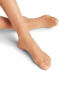Calze a mezza coscia beige con una texture liscia e trasparente, che mostrano un'area rinforzata sulla punta, posizionate accanto a un piede nudo.