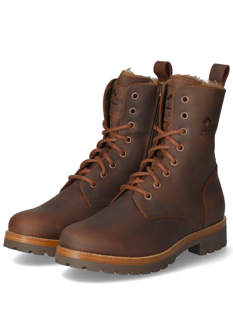 Brązowe skórzane botki sięgające kostki z sznurowanym zapięciem, bocznym zamkiem błyskawicznym, sztuczną futrzaną podszewką, okrągłym noskiem i grubą gumową podeszwą. Widoczne logo marki na kostce.