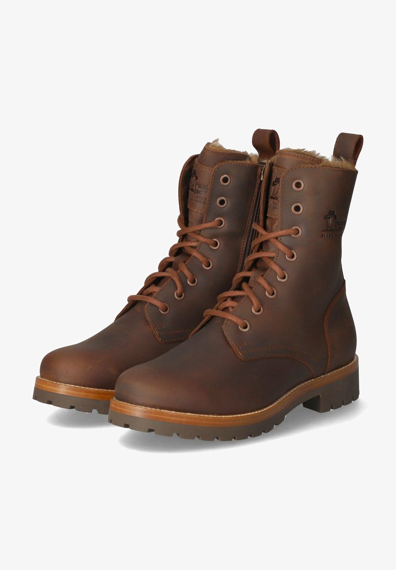 Bruine leren enkelboots met een vetersluiting, zijrits, nepbont voering, ronde neus en dikke rubberen zool. Opvallend merkembleem op de enkel.