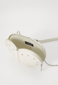 White leather handbag featuring studded accents, dual zipper compartments, and a silver chain strap. Inside lined with soft fabric.