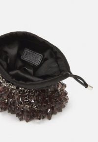 Czarny satynowy woreczek na sznurek z kryształowym zdobieniem na dole i metką z logo wewnątrz. Posiada srebrne akcenty łańcucha.