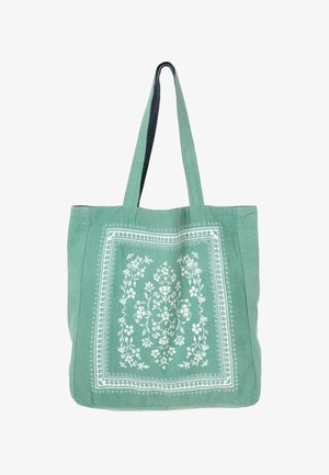 Green fabric tote bag with white floral pattern in the center and two long shoulder straps.