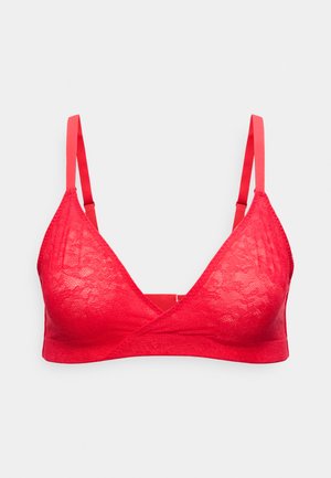 Κόκκινο bralette δαντέλας με ρυθμιζόμενους λεπτούς ιμάντες και εμπρός σε στυλ τύλιγμα, σε ανοιχτό γκρι φόντο.