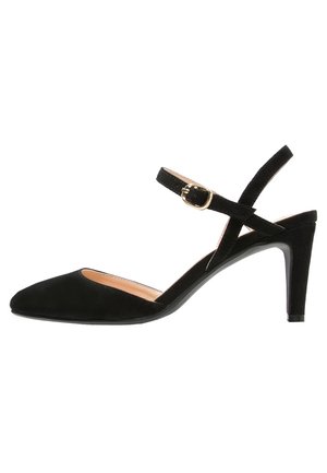 Zapato de tacón alto de ante negro con puntera afilada y tacón delgado. Cuenta con una correa en el tobillo con detalles de hebilla dorada.