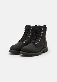Botas de tobillo de cuero negro con cordones, punta redonda, suela resistente y cremallera lateral. Superficie texturizada con ojales plateados para los cordones.