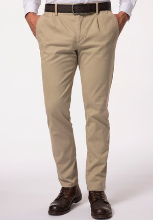 Pantalones de algodón beige con un corte recto, que cuentan con bolsillos laterales, un cinturón de cuero marrón y se combinan con botas marrones con cordones.