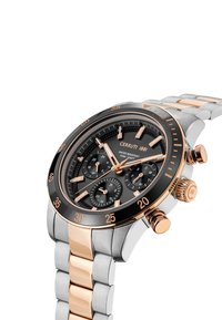 Cerruti 1881 klocka med svart urtavla, band i guld och silver av rostfritt stål, kronografsubskivor och en svart bezel med guldmarkeringar.