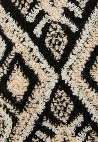 Tela negra con un patrón texturizado de diamantes y detalles florales en crema y rosa, acentuada con hilo metálico.
