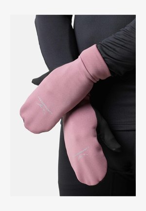 Persona che indossa abiti neri e guanti rosa SwedenMount con loghi, mani incrociate in vita contro uno sfondo semplice.