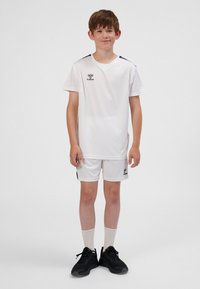 Vitt fotbollsklädsel med kortärmad tröja och shorts, markerade med svarta detaljer, gjorda av lättviktigt tyg. Bärs med svarta sportskor.