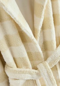 Krämfärgad, fluffig badrock med rutmönster, med ett knytbart bälte och mjukt, texturerat tyg för värme och komfort.