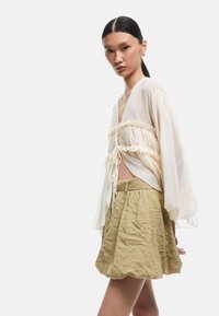 Crème, doorschijnend, langskap blouse met plooidetails en een trekkoord, gecombineerd met een textuur, hoge taille olijfgroene rok.