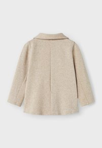 Cappotto beige con colletto, maniche lunghe, tessuto testurizzato e un dettaglio di cucitura sul retro. Design semplice senza chiusure o tasche visibili.