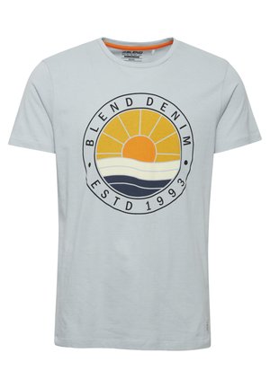 Világoskék pamut póló, kör alakú grafikával, ami egy sárga napot, fehér és sötétkék hullámokat tartalmaz, valamint a "BLEND DENIM ESTD 1993" feliratot.