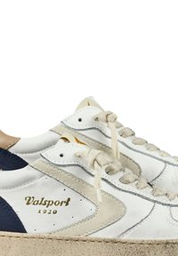 Sneaker in pelle con una parte superiore bianca e dettagli navy e crema, con lacci tondi e una suola beige texturizzata. Logo dorato "Valsport 1920" visibile.
