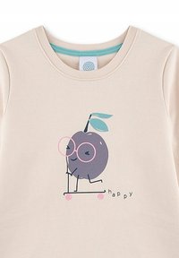 T-shirt in cotone beige con un cartoon di un frutto viola con occhiali su un monopattino rosa, con il testo "happy" sotto in nero.