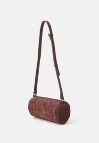 Borsa a tracolla in suede marrone, dalla forma cilindrica, con un design intrecciato su un lato e un accento circolare sull'altro.