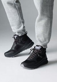 Zwarte high-top sneakers met textuurpanelen, grijze accenten en dikke zolen. Gecombineerd met grijze tapered sweatpants.