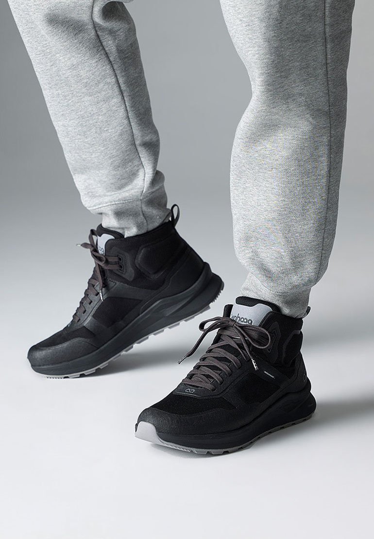 Zwarte high-top sneakers met textuurpanelen, grijze accenten en dikke zolen. Gecombineerd met grijze tapered sweatpants.