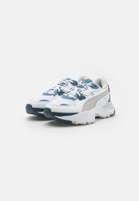 Zapatillas blancas y azul claro con parte superior de malla, cuello acolchado, suela de goma y acentos texturizados para agarre y estabilidad.