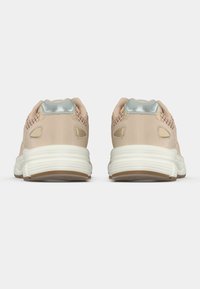 Υπόδηση με ελαφρώς ροζ συνθετικό επάνω μέρος με λεπτομέρειες από δίχτυ, ασημένια λεπτομέρεια στη φτέρνα και υφασμένο λευκό καουτσούκ στην σόλα.