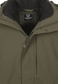 Olijfgroene waterdichte jas met een zwart gevoerde capuchon, ritssluiting aan de voorkant, drukknoopsluiting en verstevigde naden. Tenson merklabel zichtbaar.