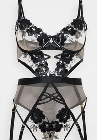 Svart blonde lingerie-set med blomsterbroderi, gjennomsiktig mesh-stoff, justerbare stropper og gullaksenter i en strukturert design.