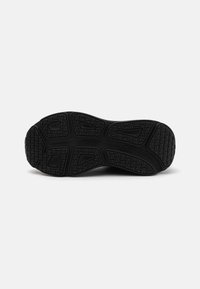 Suela de zapato atlético negro con una superficie de goma texturizada que presenta patrones de zigzag y tacos triangulares para tracción y agarre.