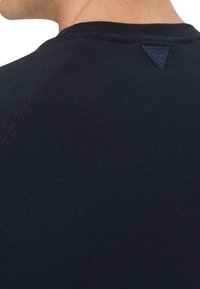 T-shirt blu navy con scollo rotondo, caratterizzata da una texture a coste, cuciture piatte e un'etichetta triangolare con logo sul retro del collo.